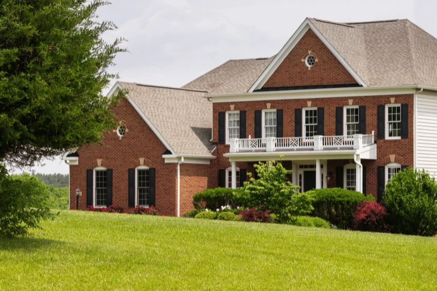 large brick home with a beautiful front porch and large front yard